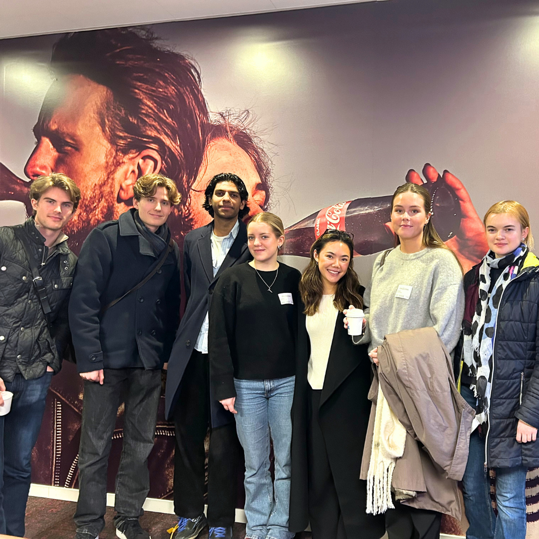 Retail Management students in line in front of a coca-cola photo wallpaper.