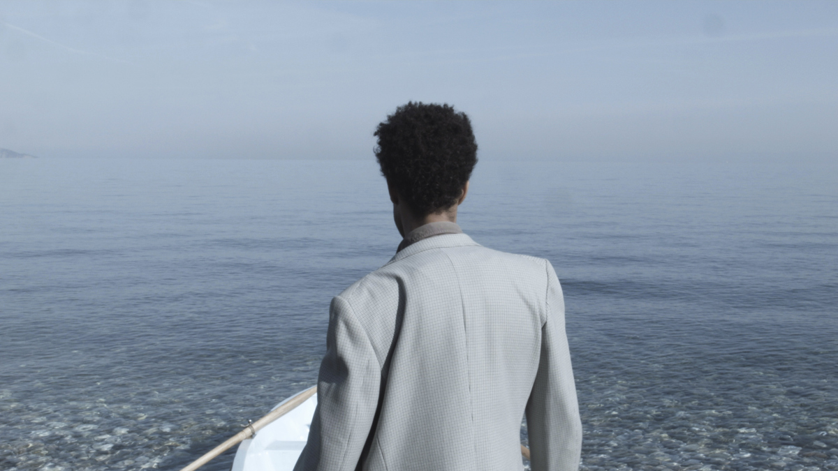 Still from Santiago Mostyn's film Citizen, showing the artist rowing a small boat across open sea 