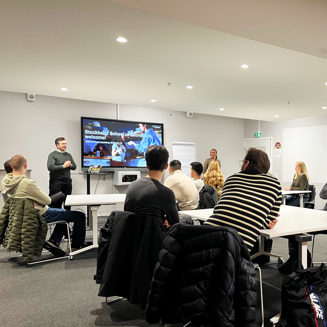 A representative from Axfood is presenting in front of students in a conference room.