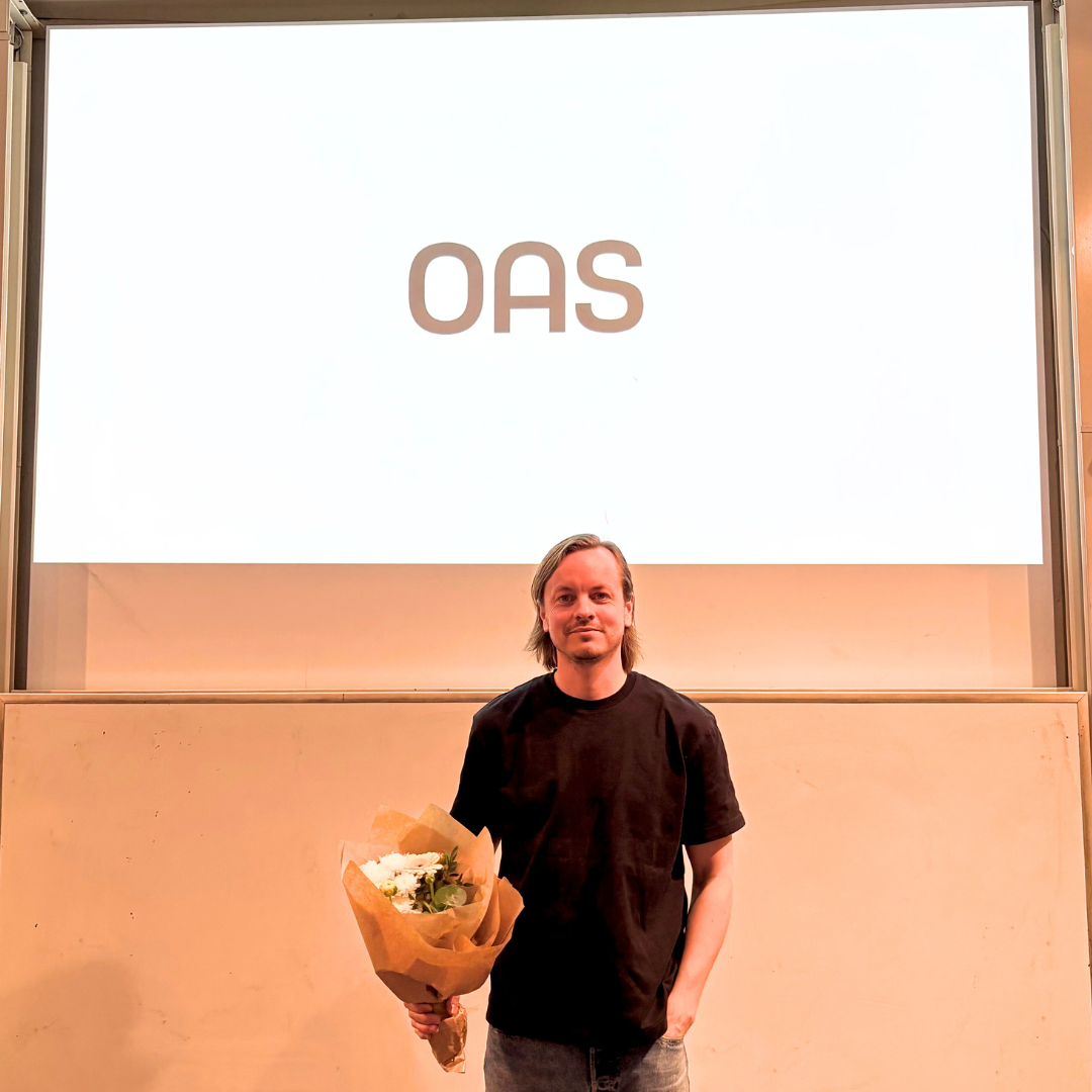 Oliver Lundgren, founder OAS, standing with thank you flowers in front of a ppt slide.
