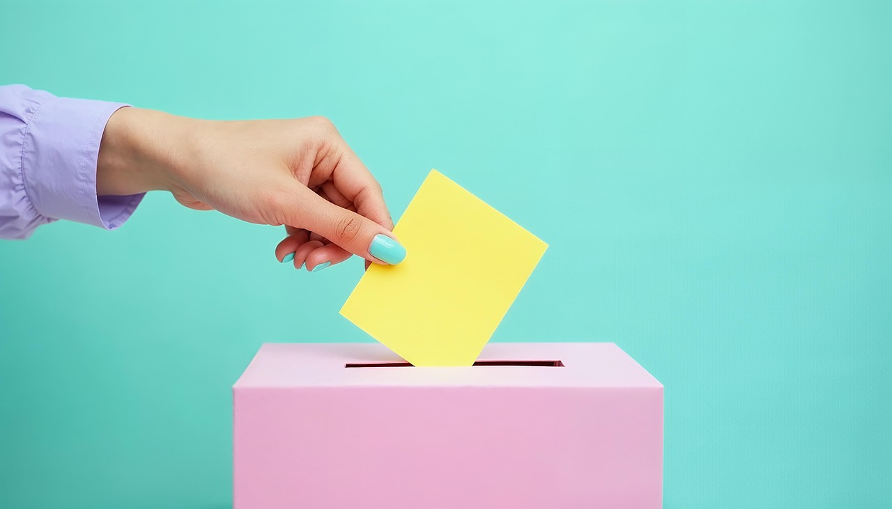 Hand placing a ballot into a ballot box