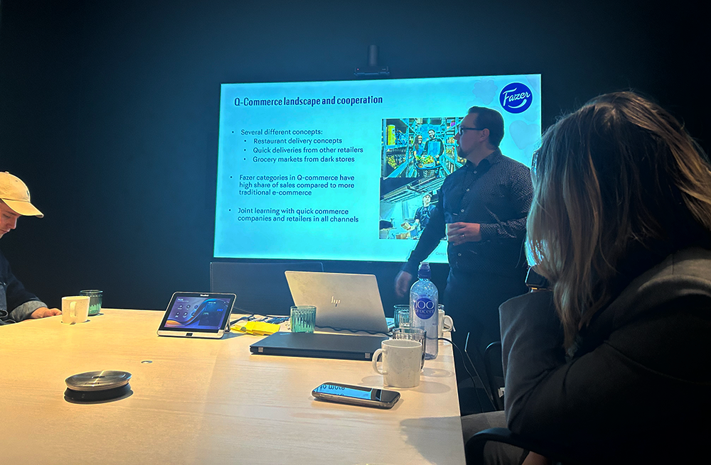 Rep from Fazer run a presentation in front of a large monitor in a dark lit room