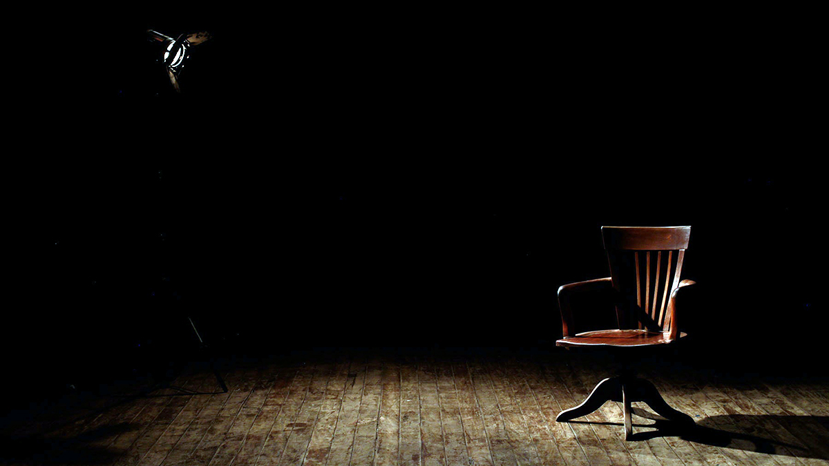 A chair and a lamp in a dark room.