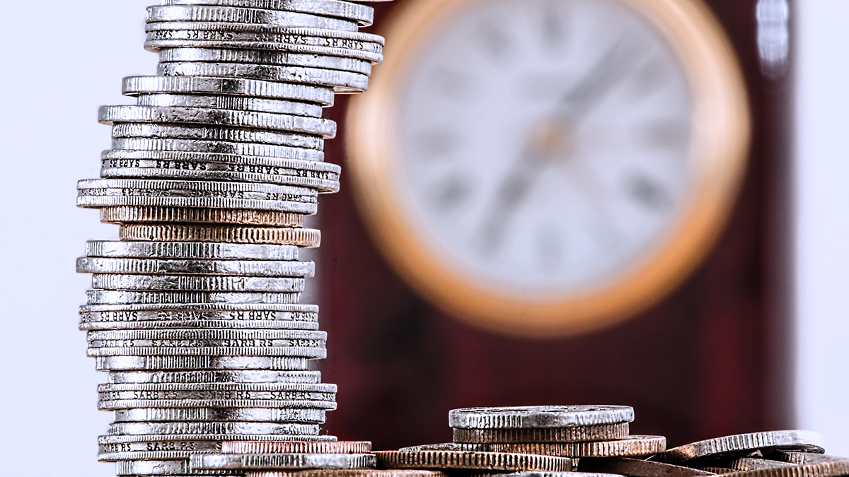 Coins stack to each other, a watch behind the scene