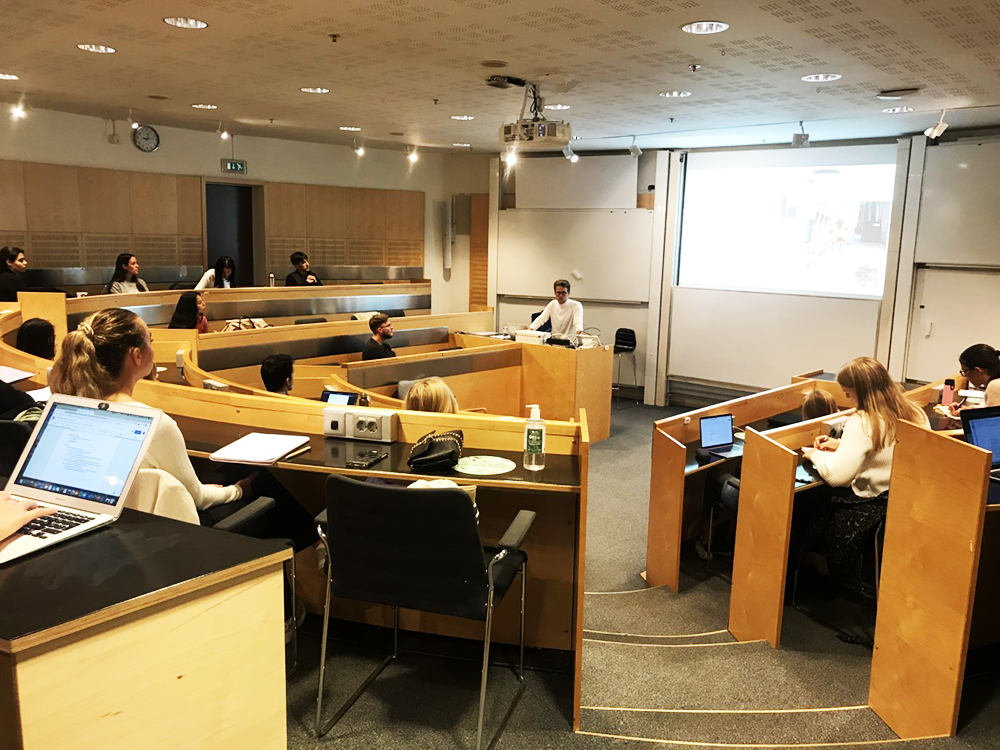 Representative from the company HM runs a presentation to students sitting in a half circle formed lecture room