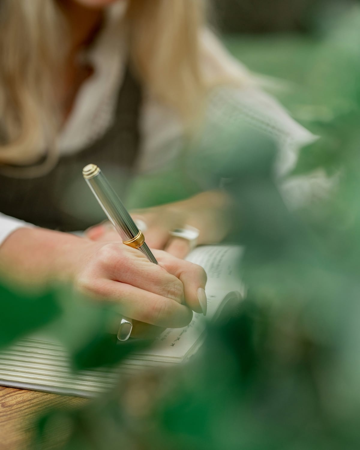 Woman writing in a notebook with foliage in the foreground
