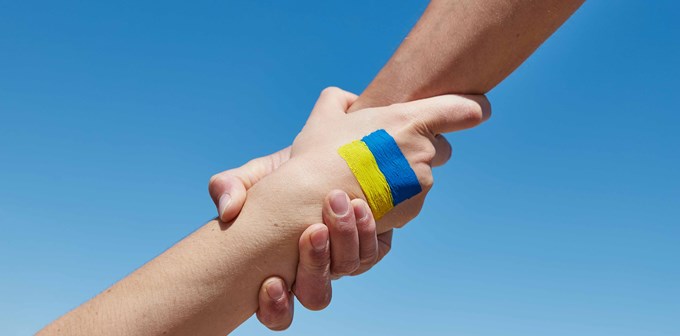 Lend a hand help painted in ukrainian flag colors against blue sky. Stand with Ukraine