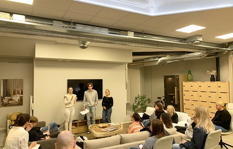 Students presenting in a high ceiling studio room