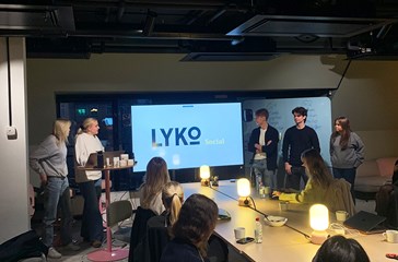 Students presenting a case at Lyko in a dark lit conference room.