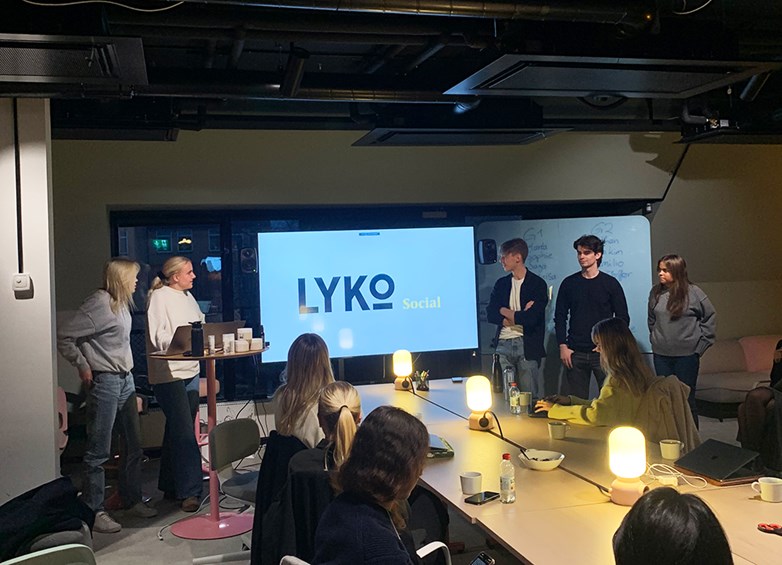 Students presenting a case at Lyko in a dark lit conference room.