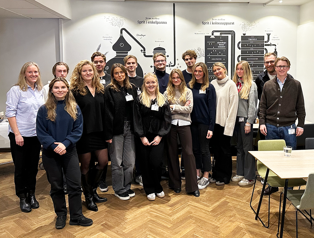 Group of students standing in line at Systembolaget HQ smiling into the camera.