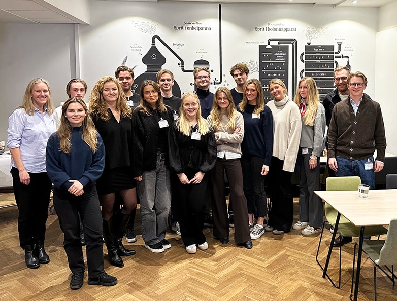 Group of students standing in line at Systembolaget HQ smiling into the camera.