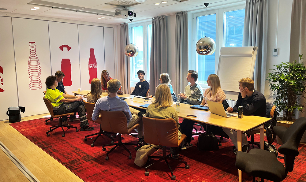 Representative from Coca-Cola meeting a group of students sitting around a table.