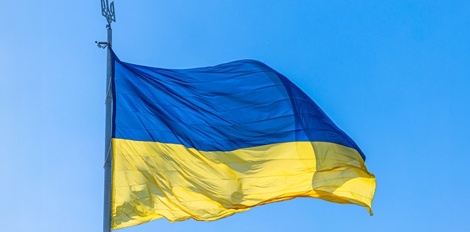 The national flag of Ukraine flies on wind in the blue sky