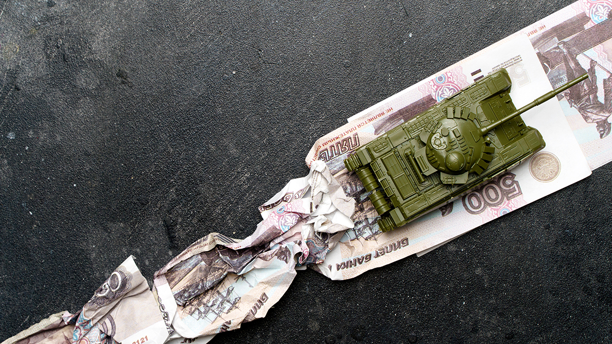 Economic crisis in Russia concept. Toy military tank on Russian rubles. War conflict in Ukraine, economic sanctions and inflation in Russia.