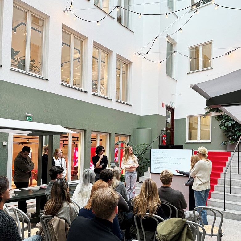 Students presenting in an atrium at H&M HQ, Stockholm.