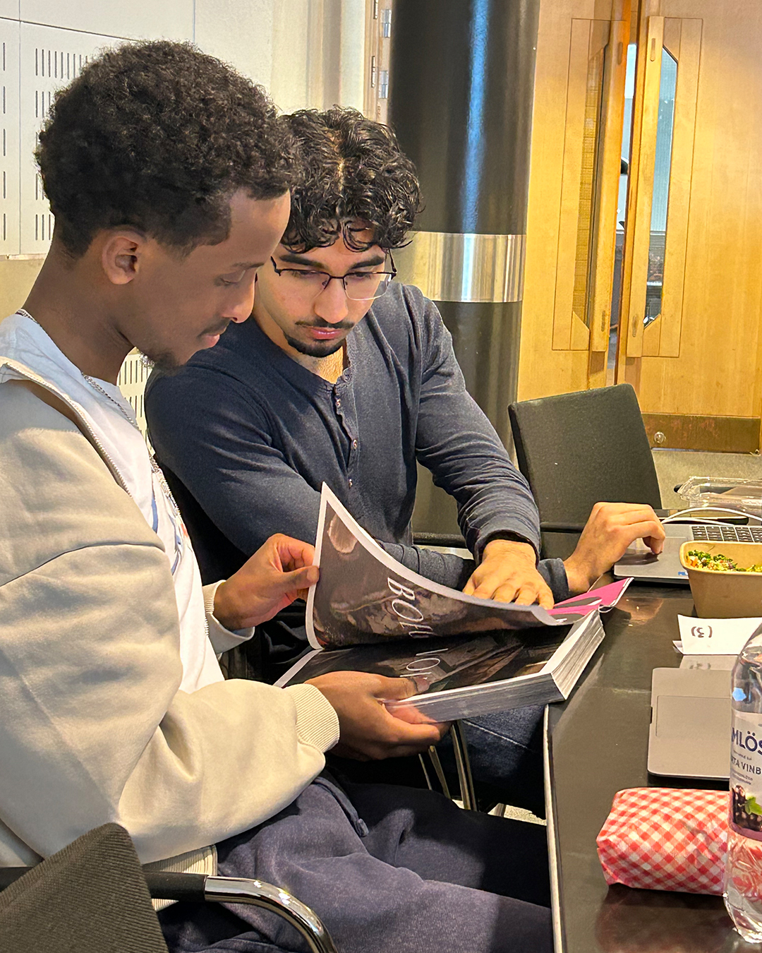 Students flip through a book with AI-generated marketing images, while discussing the potential and limitations of using AI in branding.