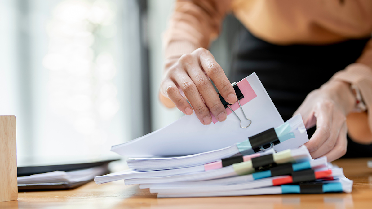 Businesswoman hands working in Stacks of paper files for searching and checking unfinished document achieves on folders papers at busy work desk office