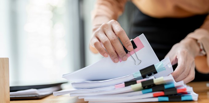 Businesswoman hands working in Stacks of paper files for searching and checking unfinished document achieves on folders papers at busy work desk office