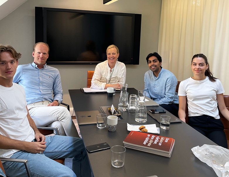 Maria Mellander at Axel Johnson sitting around a table with students smiling and looking into the camera.