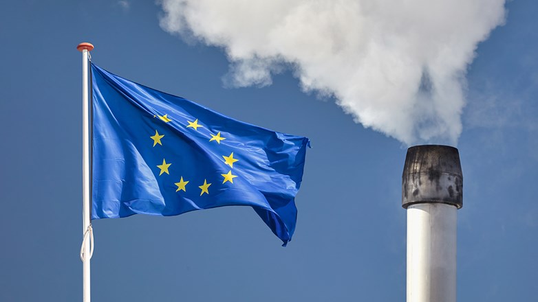 EU flag in front of a polluting factory chimney with smoke