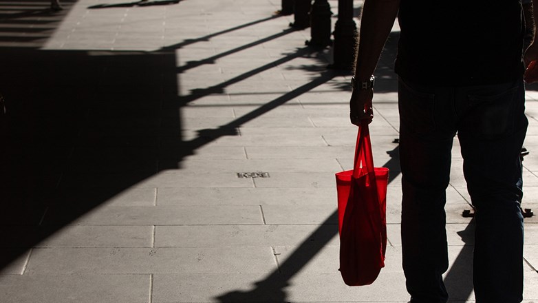 Man walking in the street while holding a bag