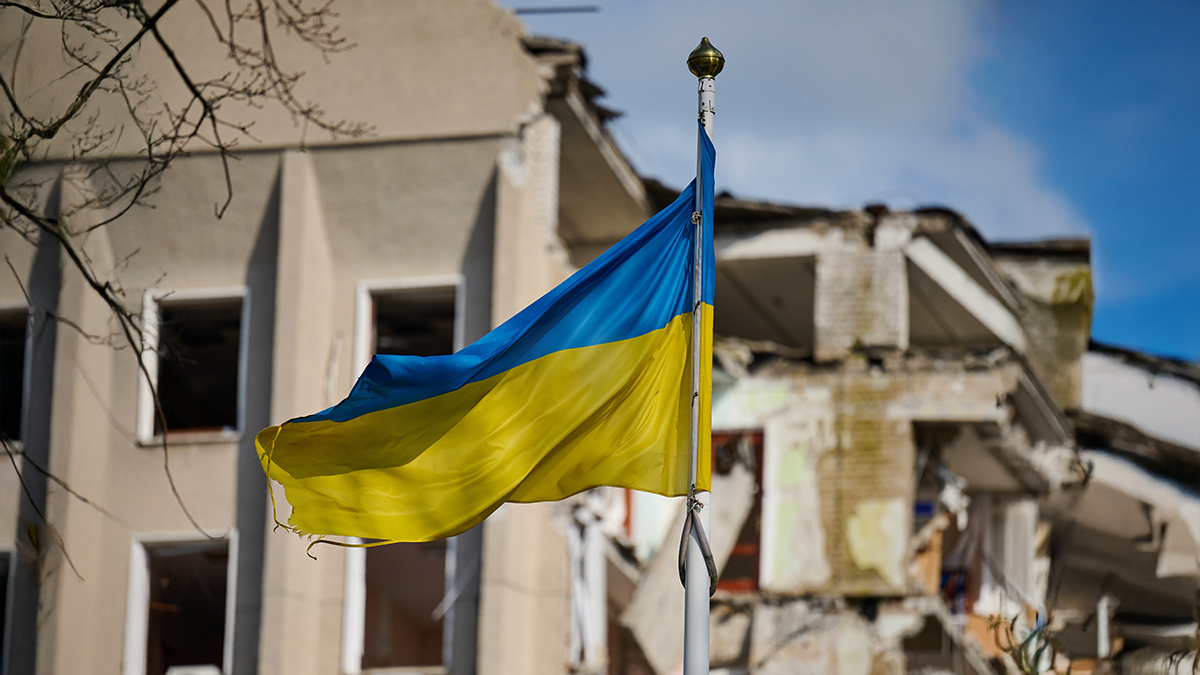 Flag of Ukraine against the background of a destroyed building in Ukraine. The building was destroyed by a Russian air bomb.