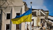 Flag of Ukraine against the background of a destroyed building in Ukraine. The building was destroyed by a Russian air bomb.