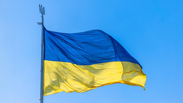 The national flag of Ukraine flies on wind in the blue sky