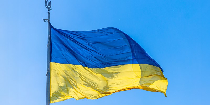 The national flag of Ukraine flies on wind in the blue sky