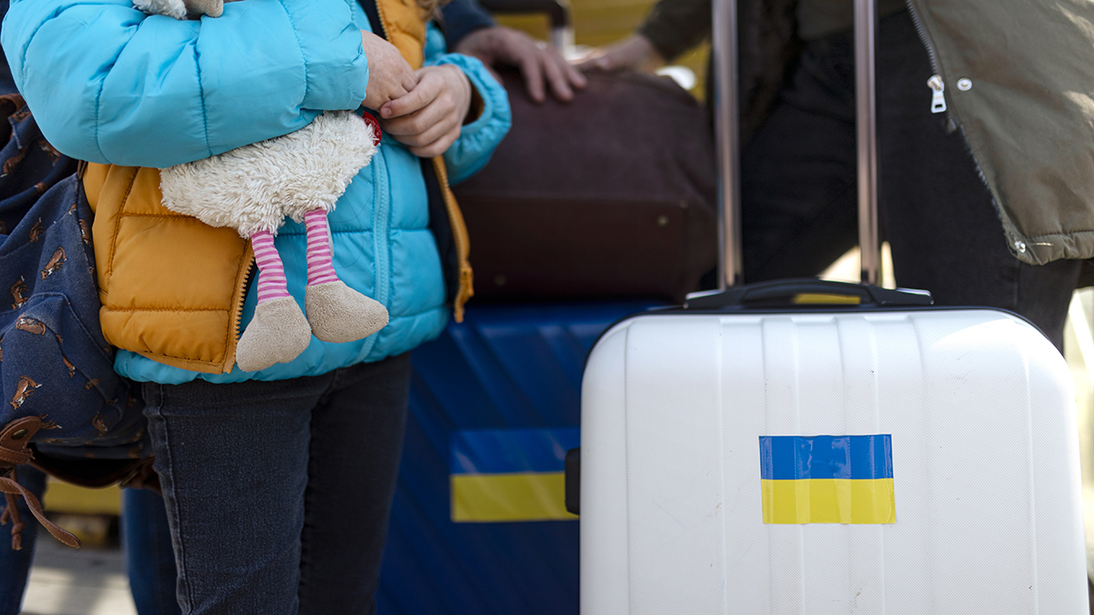 Close-up of Ukrainian immigrants with luggage waiting at train station.