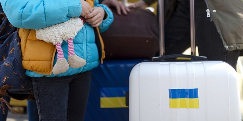 Close-up of Ukrainian immigrants with luggage waiting at train station.