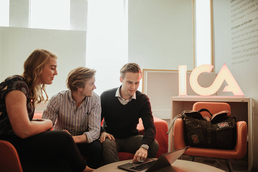 Students working in front of an laptop in a room with ICA neon sign