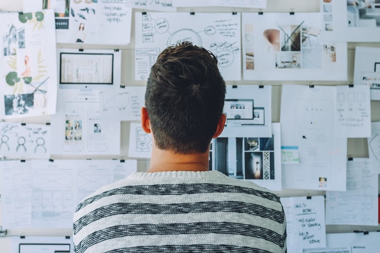 Person sitting in front of a board with many different papers