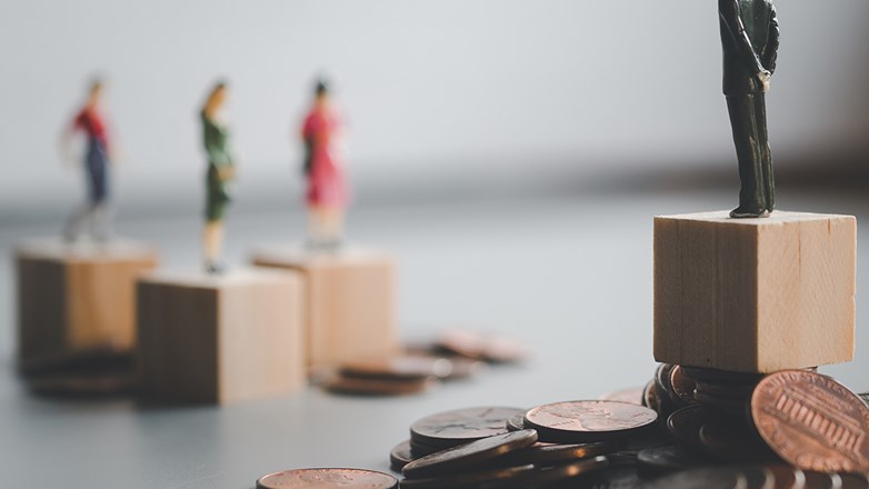 Man standing on a pile of money, looking down on three people with less money.