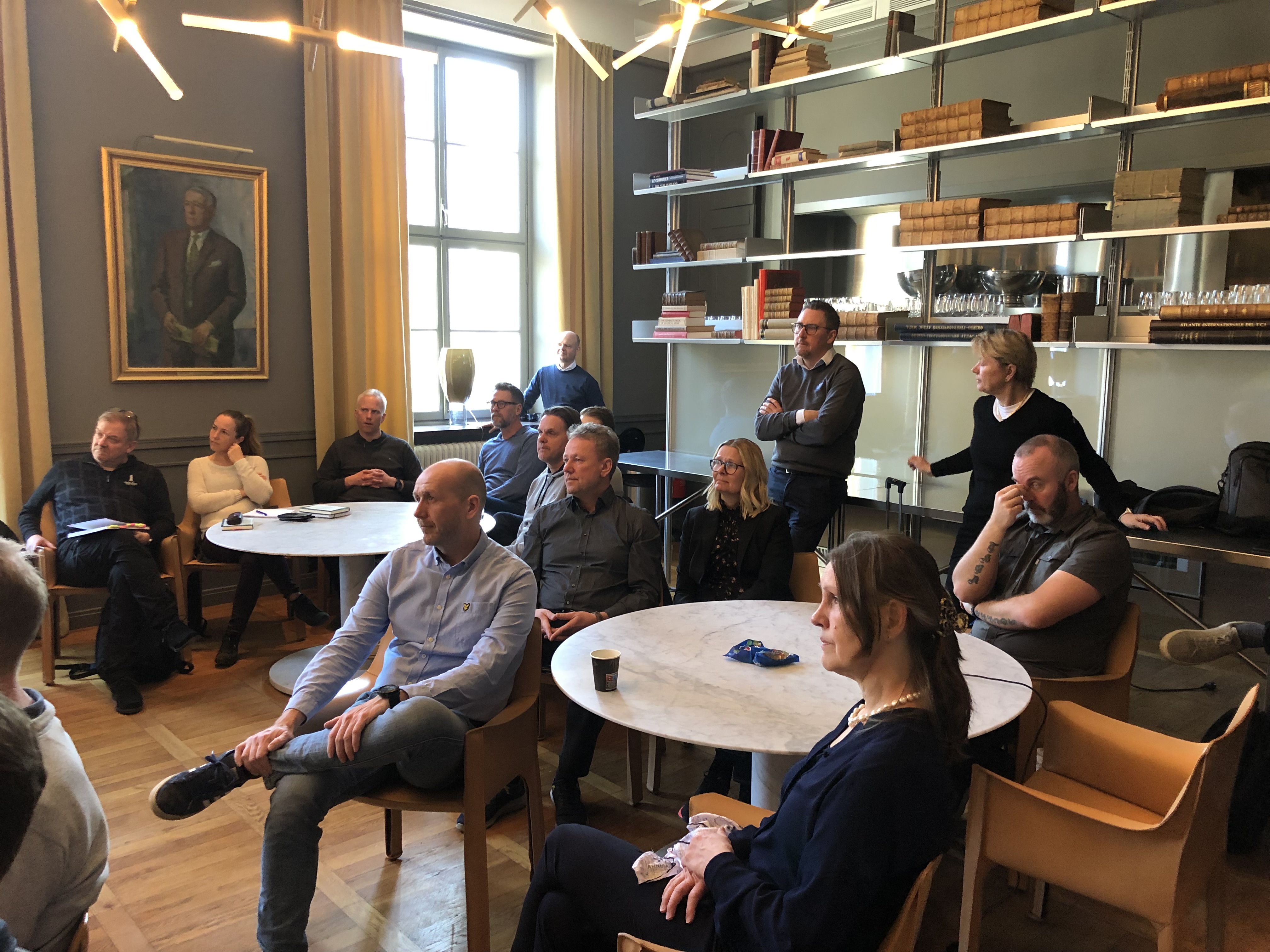 People sitting on chairs in a room and listen to a presentation