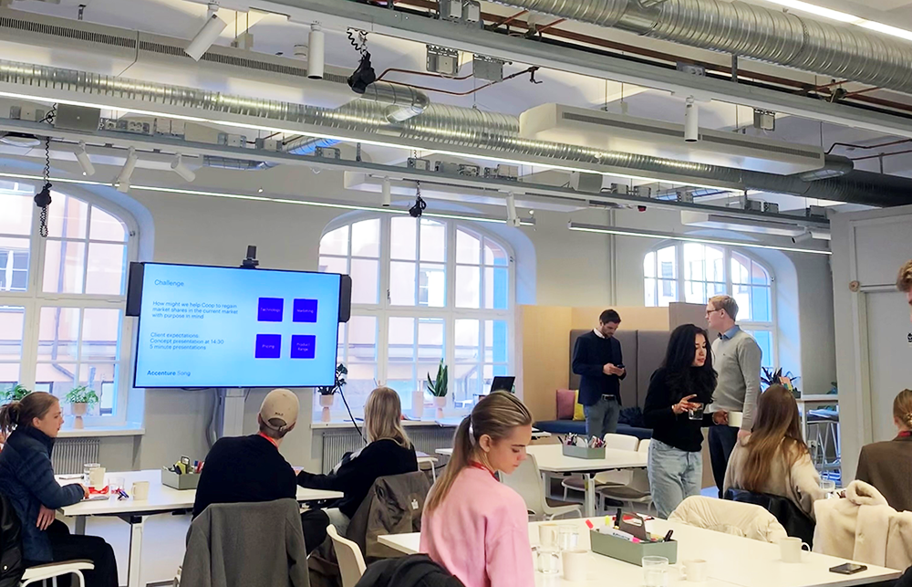 Students discussing, move, and sit around tables at a workshop with Accenture.