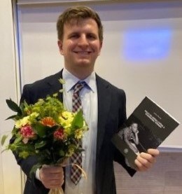 Andrew Proctor holding his thesis and the flowers