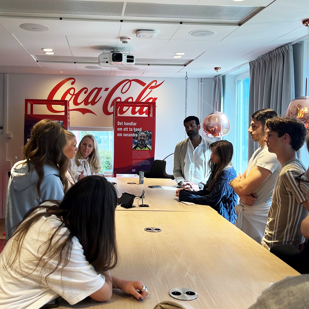 Students around a smaller conference table talking to representatives from Coca-Cola Europacific Partners.