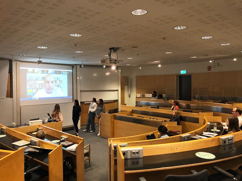 Students looking at a video broadcast with Axel Johnson in a lecture room