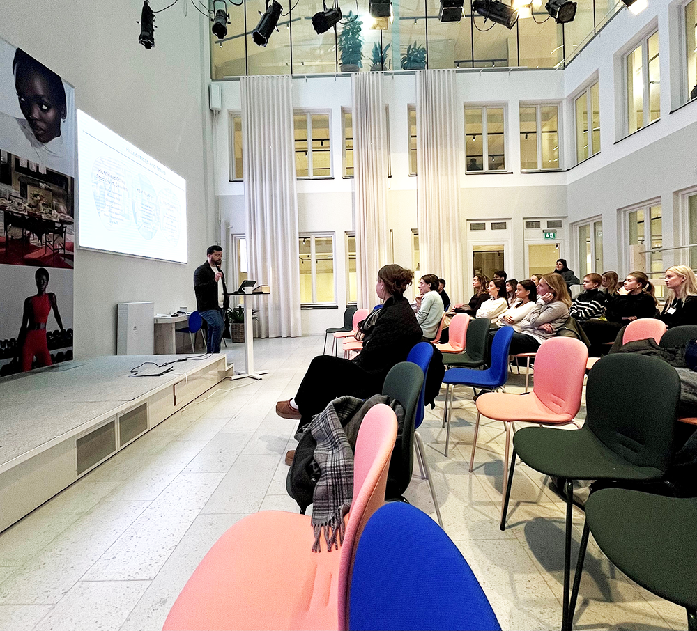 Representative from H&M hold a presentation at H&M's HQ in front a group of students.