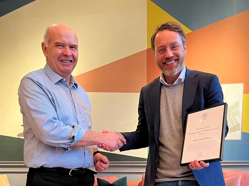 two persons shaking hands and watching into the camera