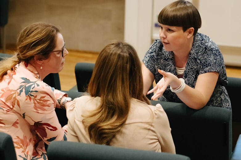 Two women listening to another woman talking