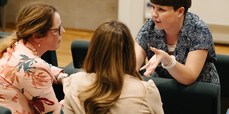 Two women listening to another woman talking