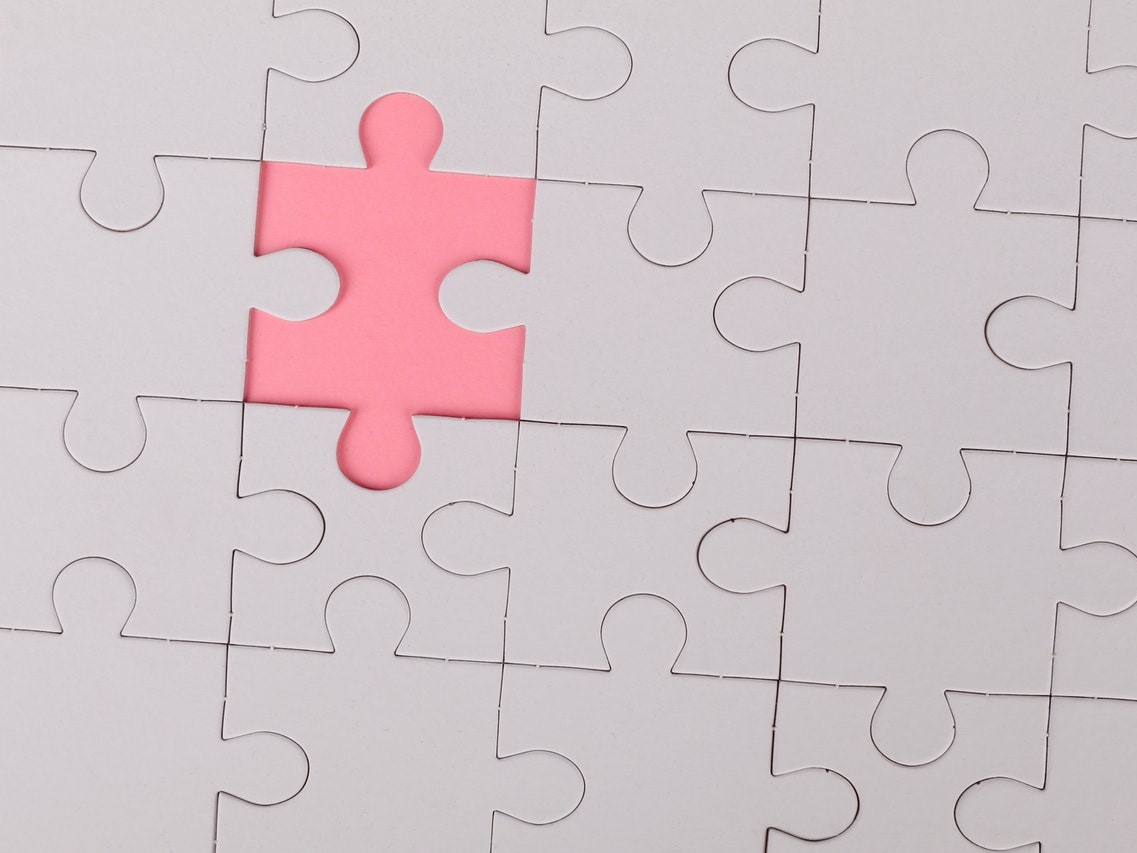 White puzzle with the final piece in pink