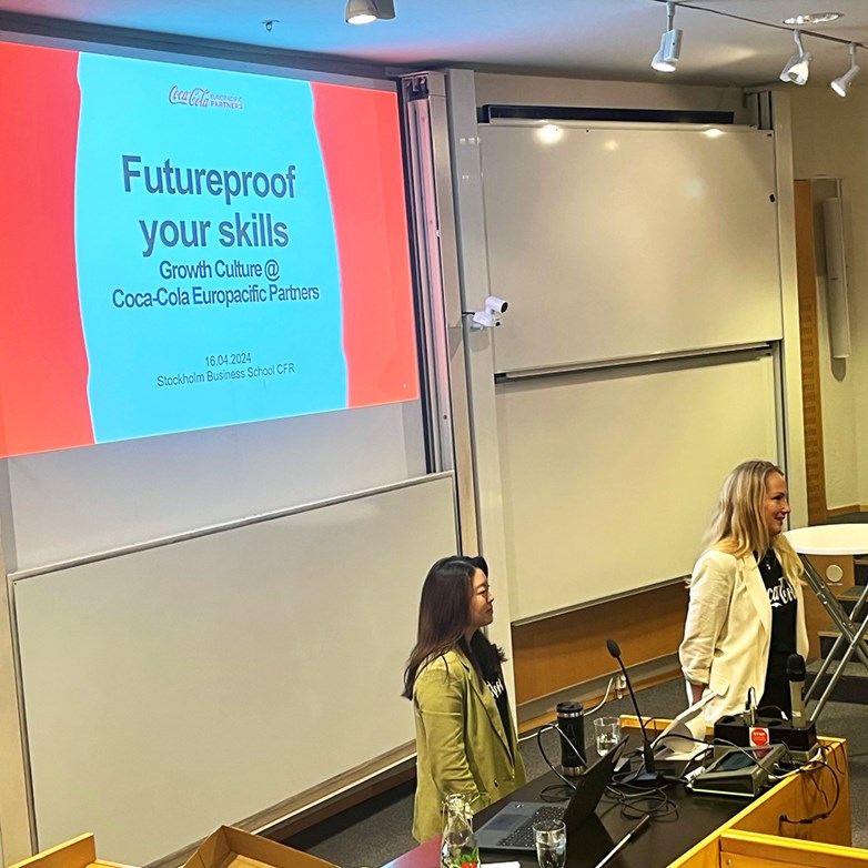 Representatives from Coca-Cola Europacific Partners holding a lecture in front of a projector screen.