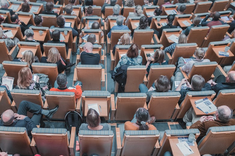 A crowd of people shot from above, sitting in a lecture hall.