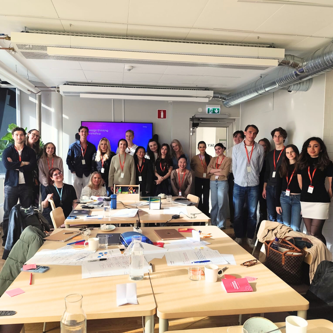 Students standing around a konference table at Accenture HQ, Stockholm