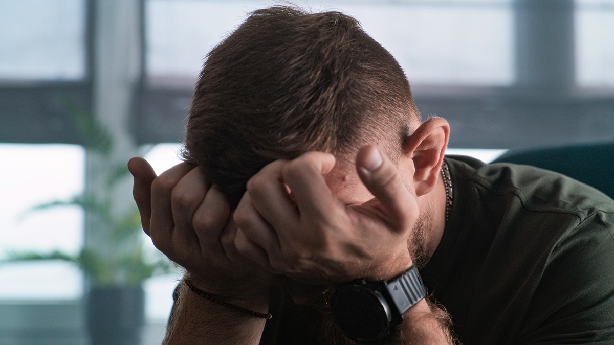 Close up of depressed military man with contusion or PTSD crying during rehabilitation after war or counseling session. Soldier talks to psychotherapist or psychologist. Post traumatic stress disorder.