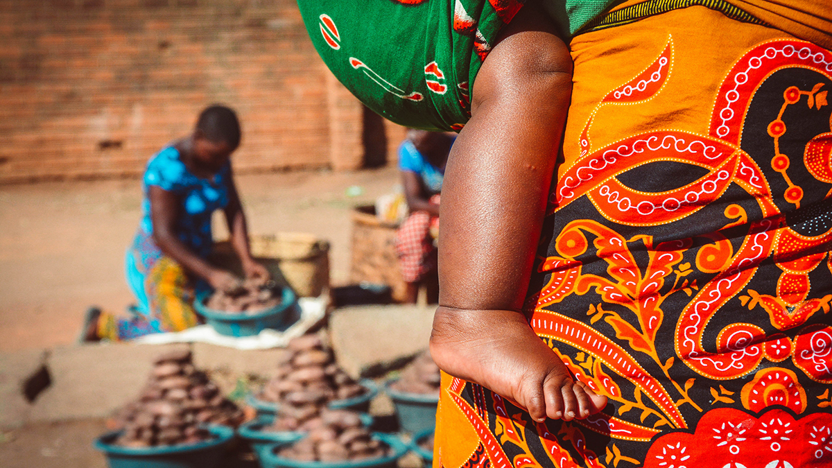 African woman is carrying her baby on the market